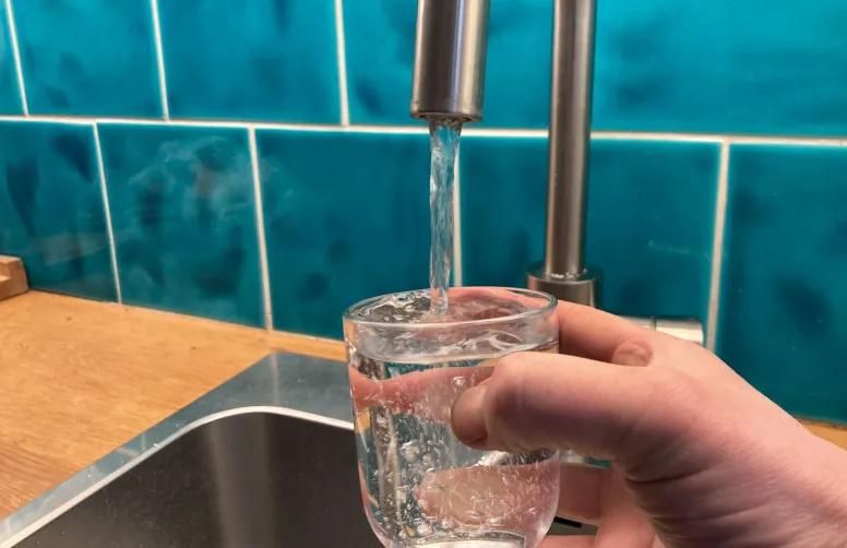 De l'eau du robinet est recueillie dans un verre