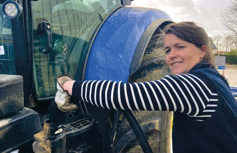 Une agricultrice remplit le réservoir de son tracteur avec du carburant. 