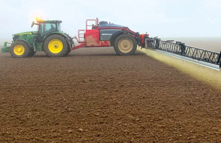 Un tracteur épand un herbicide sur un sol nu (application de prélevée).