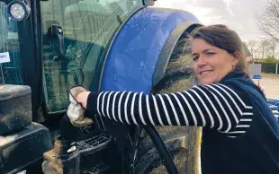 Une agricultrice remplit le réservoir de son tracteur avec du carburant. 