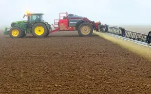 Un tracteur épand un herbicide sur un sol nu (application de prélevée).